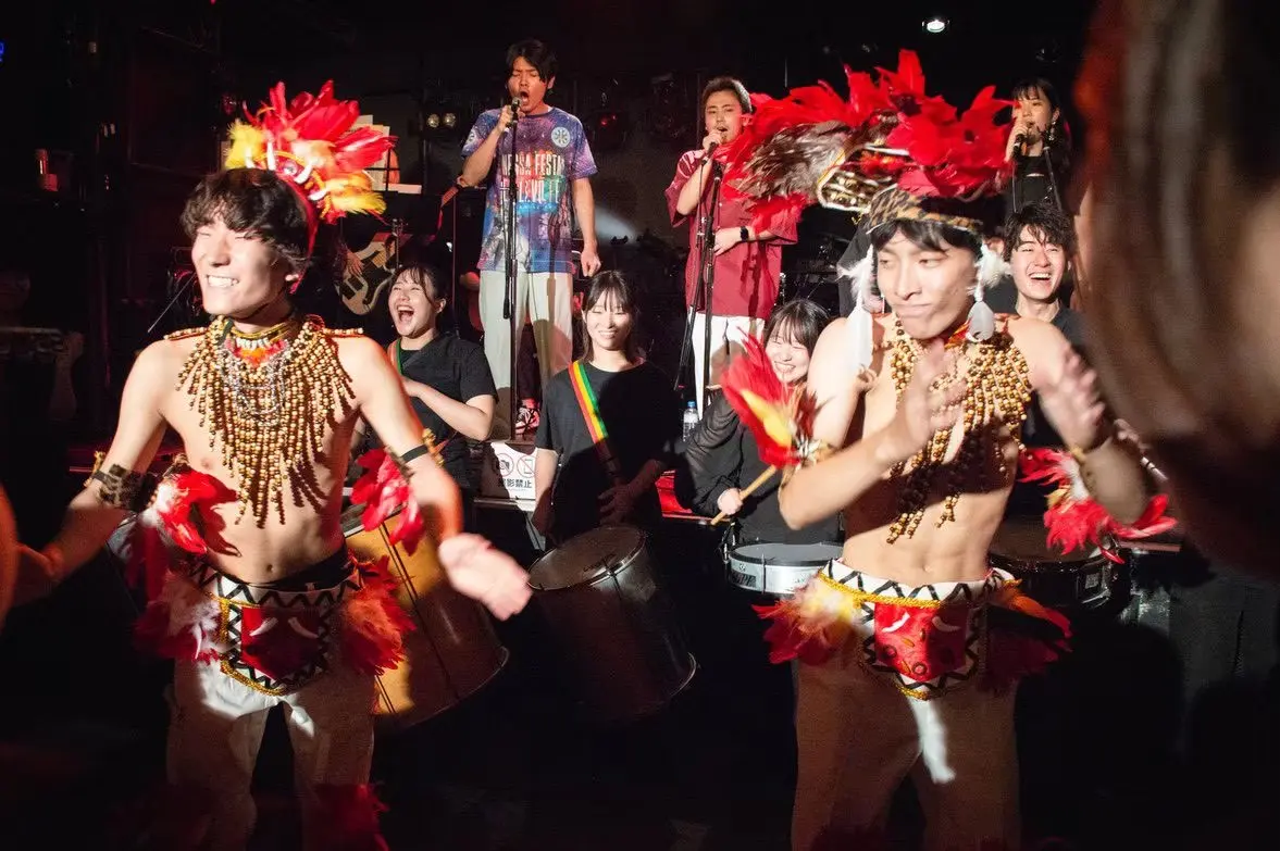 羽根飾りの衣装で踊るボイブンバのダンサーと演奏するメンバー